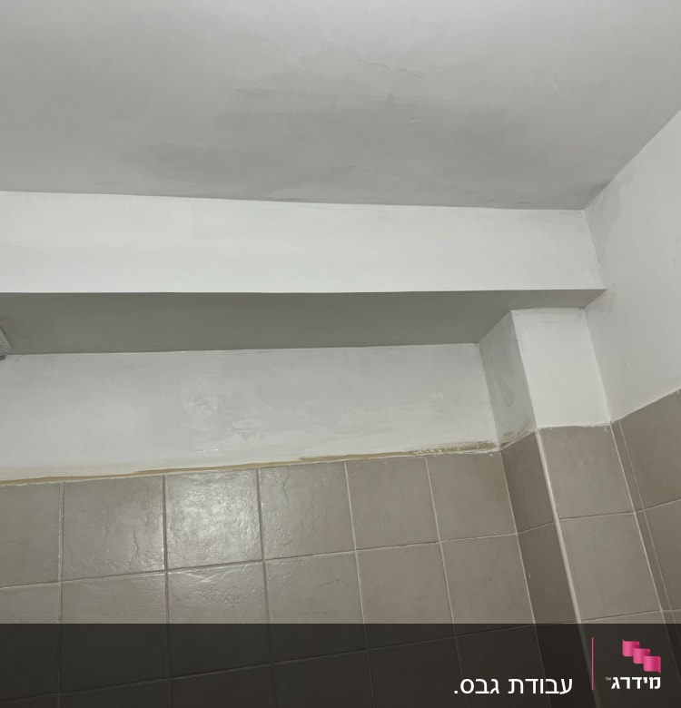 קיר גבס צבוע בלבן עם אריחים חומים